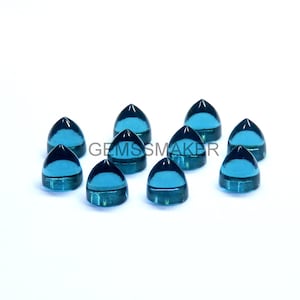 May include: Ten blue-green, teardrop-shaped gemstones with a dark blue top are displayed on a white background. The text "GEMSSMAKER" is visible in the center of the image.