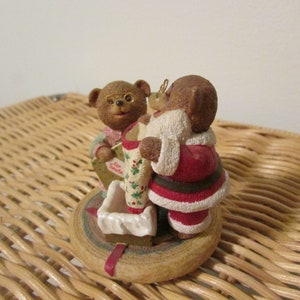 Puede incluir: Un adorno navide&ntilde;o con dos osos de peluche marrones. Un oso est&aacute; vestido de Pap&aacute; Noel y el otro sostiene una carta dirigida a Pap&aacute; Noel. El adorno est&aacute; sobre una base de madera.