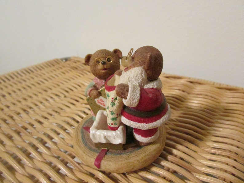 Puede incluir: Un adorno navide&ntilde;o con dos osos de peluche marrones. Un oso est&aacute; vestido de Pap&aacute; Noel y el otro sostiene una carta dirigida a Pap&aacute; Noel. El adorno est&aacute; sobre una base de madera.