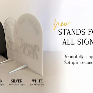 May include: Three arched acrylic signs in black, frosted, and white, each supported by a matching stand. Text on the image reads: New STANDS FOR ALL SIGNS. Beautifully simple. Setup in seconds. BLACK for black signs, SILVER for frosted signs, WHITE for white signs.