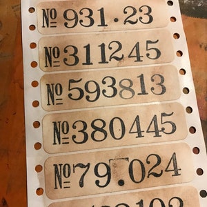 May include: A sheet of brown paper labels with black numbers printed on them. The numbers are: 738105, 931.23, 311245, 593813, 380445, 79.024, 538102.