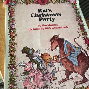 May include: A children's book cover with a festive Christmas theme. The title is "Rat's Christmas Party" by Jim Murphy, with illustrations by Dick Gackenbach. The cover features a rat wearing a blue scarf, holding a plate of food, and surrounded by other small animals.
