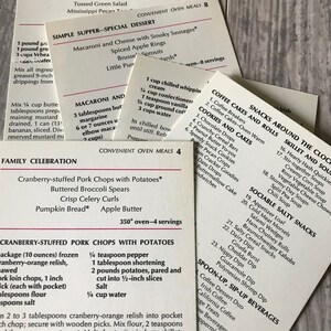 May include: A collection of recipe cards for convenient oven meals. The cards are printed with a white background and black text. The cards feature a variety of meal ideas, including baked ham dinner, simple supper, family celebration, and coffee cakes and rolls.
