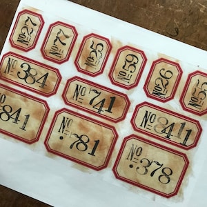 May include: Ten vintage-style paper labels with red borders and black numbers. The numbers on the labels are: 384, 841, 781, 741, 8411, 378, 59, 22, 55, 77.