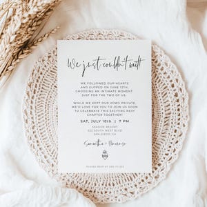 Pode incluir: Um convite de casamento creme com a frase "We just couldn't wait!" em caligrafia elegante. O convite está colocado sobre uma toalha de crochê bege e tecido branco. O texto inclui a data, hora e local do evento.