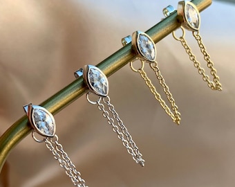 Puede incluir: Cuatro pares de pendientes con piedras transparentes de forma marquesa y cadenas colgantes. Dos pares tienen cadenas plateadas y dos pares tienen cadenas doradas.