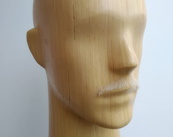 May include: A wooden mannequin head with a white faux mustache.