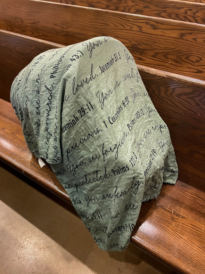 May include: A green throw blanket with black text printed on it. The text includes bible verses and phrases like "You are loved", "You are precious", and "You are family".
