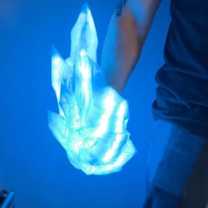 May include: A blue glowing crystal shaped like a hand, held by a person wearing a blue shirt.
