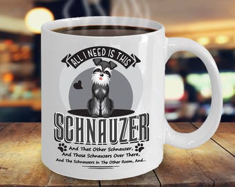 May include: White ceramic coffee mug with a black and white illustration of a miniature schnauzer. The mug has the text "All I need is this Schnauzer" and "And that other Schnauzer, And those Schnauzers over there, And the Schnauzers in the other room, And..." printed on it.