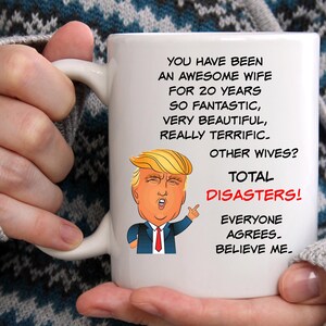 May include: White ceramic coffee mug with a humorous image of a cartoon Donald Trump and the text "You have been an awesome wife for 20 years so fantastic, very beautiful, really terrific. Other wives? Total disasters! Everyone agrees. Believe me."