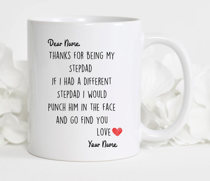 May include: White ceramic coffee mug with black text that reads "Dear Name, THANKS FOR BEING MY STEPDAD IF I HAD A DIFFERENT STEPDAD I WOULD PUNCH HIM IN THE FACE AND GO FIND YOU LOVE Your Name" with a red heart.