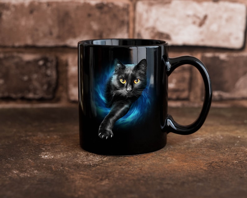 May include: Black ceramic mug featuring a black cat with yellow eyes emerging from a blue and black swirling design. The mug has a black handle and is set against a brick wall background.