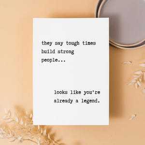 May include: A white card with black text that reads "they say tough times build strong people... looks like you're already a legend."