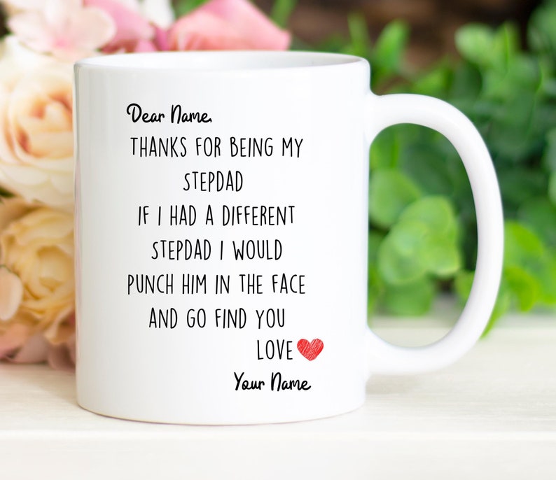 May include: White ceramic mug with a black and red design. The mug reads "Dear Name, THANKS FOR BEING MY STEPDAD IF I HAD A DIFFERENT STEPDAD I WOULD PUNCH HIM IN THE FACE AND GO FIND YOU LOVE Your Name".