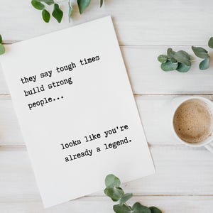 May include: A white card with black text that reads "they say tough times build strong people... looks like you're already a legend."