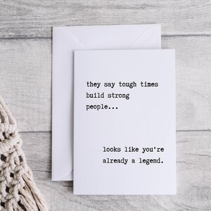 May include: A white card with black text that reads "they say tough times build strong people... looks like you're already a legend."