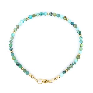May include: A delicate bracelet featuring small, faceted turquoise beads in shades of blue and green, interspersed with tiny, polished gold-tone metal spacer beads. The piece is secured with a gold-tone lobster claw clasp at the bottom.