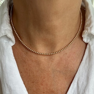 May include: A gold beaded necklace with small, round beads. The necklace is delicate and simple, and would make a great everyday piece of jewelry.