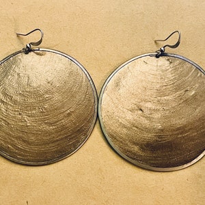 May include: A pair of large, round, silver earrings with a textured, metallic finish.