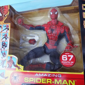 Puede incluir: Figura de acci&oacute;n de Amazing Spider-Man en un embalaje de pl&aacute;stico transparente. La figura es roja y negra, con un emblema de ara&ntilde;a en el pecho. El embalaje incluye el texto "WITH 67 POINTS OF ARTICULATION!"