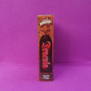 May include: A rectangular box featuring the Universal Studios Monsters logo and the name "Dracula" in red script. The box is brown with a brick wall design and a bat graphic. The text "COLLECTIBLE RENFIELD 12" FIGURE" is at the bottom.