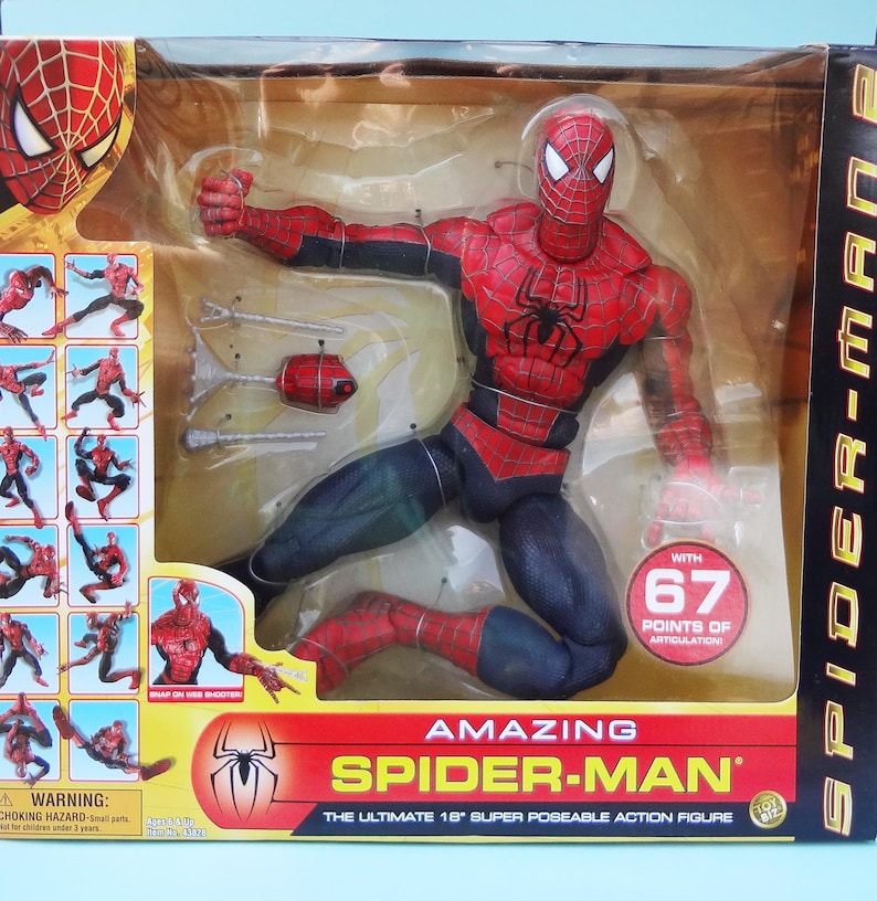 Puede incluir: Figura de acci&oacute;n de Amazing Spider-Man en un embalaje de pl&aacute;stico transparente. La figura es roja y negra con un emblema de ara&ntilde;a en el pecho. El embalaje incluye el texto "Amazing Spider-Man" y "La figura de acci&oacute;n s&uacute;per posable de 45.7 cm."