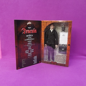 May include: A Dracula Bela Lugosi action figure in a display box. The figure wears a black coat, white shirt, and purple pants. Accessories include a briefcase, lantern, and a document. The box features the movie title and cast list.