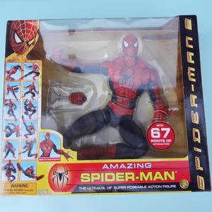 Puede incluir: Figura de acci&oacute;n de Amazing Spider-Man en una caja de presentaci&oacute;n de pl&aacute;stico transparente. La figura es roja y azul con detalles en negro. El embalaje incluye el logotipo de Spider-Man y el texto "The Ultimate 18" Super Poseable Action Figure."