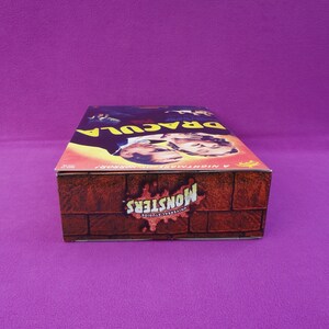 May include: A vintage Universal Monsters "Dracula" box. The top features a movie poster with the title "Dracula" and images of the actors. The sides have a brick wall design with the "Monsters" logo.