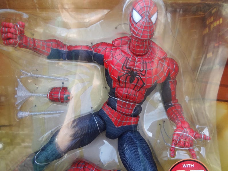 Puede incluir: Figura de acci&oacute;n de Spider-Man en un embalaje de pl&aacute;stico transparente. La figura es predominantemente roja y azul, con un emblema de ara&ntilde;a negra en el pecho. Presenta patrones de telara&ntilde;a detallados y accesorios.