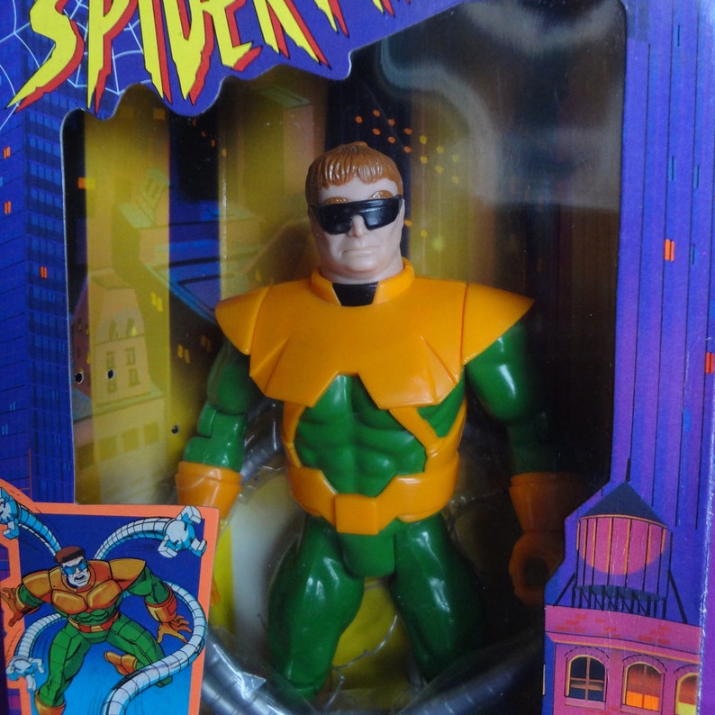 May include: A green and orange action figure of Doctor Octopus from Spider-Man. He is wearing a green and orange suit with a yellow belt and has four mechanical arms. He is wearing black sunglasses.