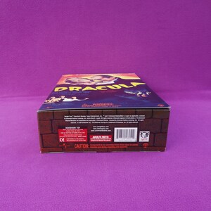 May include: A rectangular box featuring the title "DRACULA" in large, stylized letters. The box has a brick-like pattern on the sides and a movie poster design on the top, with images of characters and the film's title.