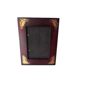 May include: A rectangular, burgundy-colored picture frame with gold floral corner accents. The frame has a dark interior and is designed to hold a photograph. The frame is made of wood and has a classic, decorative style.