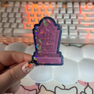May include: A holographic sticker shaped like a tombstone with the text "R.I.P. Rest in peace to my abandoned Nintendogs" on it.