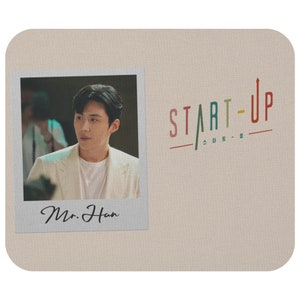 Könnte beinhalten: Ein Polaroid-ähnliches Foto eines Mannes in einem weißen Sakko mit dem Text "Mr. Han" unter dem Foto. Der Hintergrund ist eine beige Oberfläche mit dem Text "START-UP" in Regenbogenfarben.