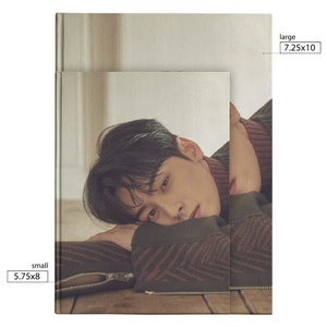 May include: A photo of a man with dark hair lying on a wooden floor. He is wearing a brown and red patterned sweater. The image is cropped to show the man's face and upper body. The text "small 5.75x8" is in the bottom left corner of the image. The text "large 7.25x10" is in the top right corner of the image.