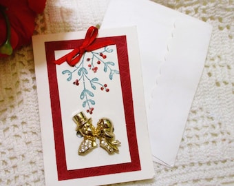 Tarjeta con broche de pareja besándose bajo el muérdago estilo vintage: joyería navideña con diamantes de imitación chapada en oro.