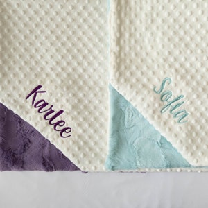 May include: Two white baby blankets with different colored backing. One blanket has the name "Karlee" embroidered in purple and the other has the name "Sofia" embroidered in blue.