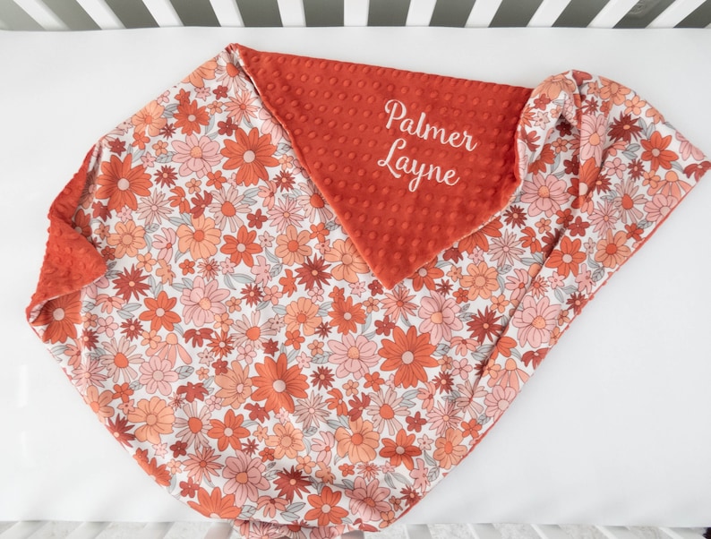 May include: A red and white floral baby blanket with a red minky backing. The blanket is personalized with the name "Palmer Layne" in white embroidery.