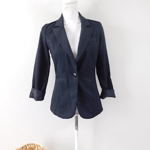 May include: A dark navy blazer with a single button fastening and notched lapels. The sleeves are three-quarter length with folded cuffs. The blazer is displayed on a white mannequin against a white background.