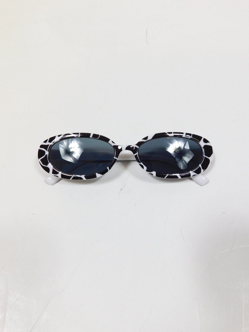 May include: Black and white oval sunglasses with a white frame and black lenses.