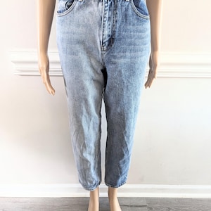 May include: Two-tone denim jeans. The left leg is light wash, the right leg is medium wash. Jeans have a button and zip closure, front and back pockets, and a relaxed fit. The jeans are displayed on a mannequin.