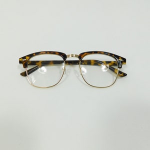 May include: Tortoise shell eyeglasses with gold metal frames and clear lenses.