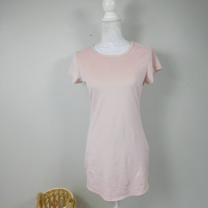 May include: A pale pink, short-sleeved t-shirt on a white mannequin.