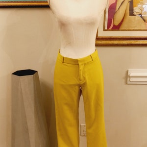 Könnte beinhalten: Eine gelbe Hose auf einem weißen Mannequin. Die Hose hat eine gerade Bein und einen Reißverschluss.