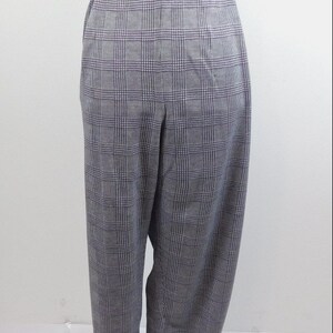 May include: Gray plaid pants displayed on a mannequin. The pants have a classic plaid pattern in shades of gray and white. The trousers have a relaxed fit and an elastic waistband.