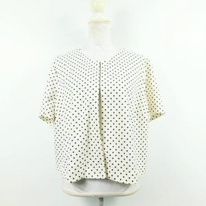 May include: A white polka dot cardigan with short sleeves and a front button closure.