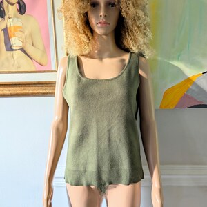 May include: A sleeveless, olive green knitted tank top with a scoop neck.