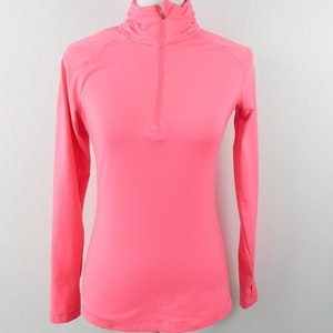May include: A pink long-sleeved shirt with a mock neck and a quarter-zip closure.